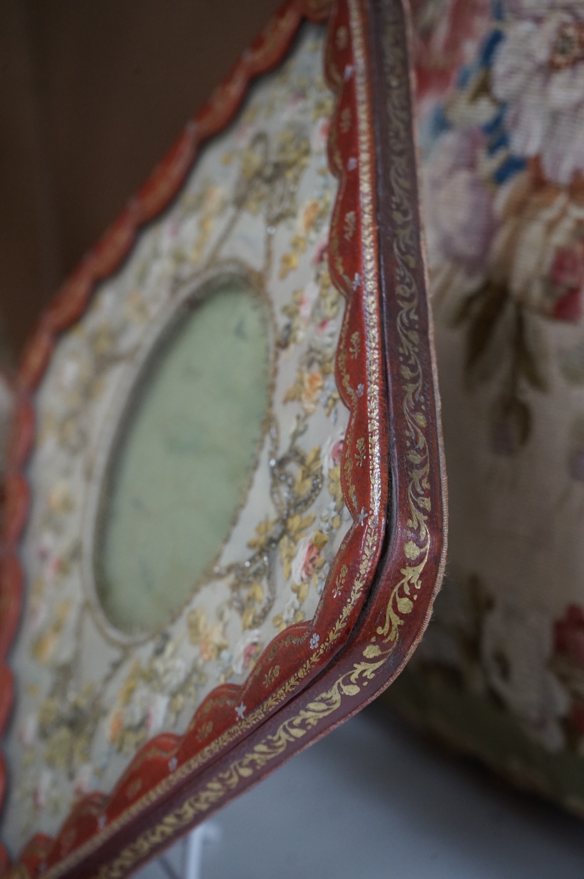 An Edwardian decorative stamped gilt leather photo frame, with bow to base and a floral patterned ribbon and sequin work front panel. 27.5cm high. Condition -good